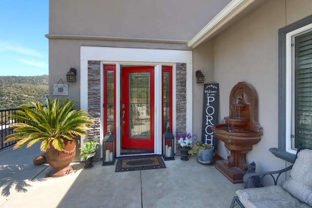doorway to property featuring stone siding and stucco siding