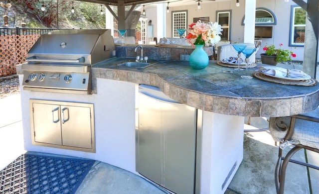 view of patio with area for grilling, an outdoor kitchen, a sink, and outdoor wet bar