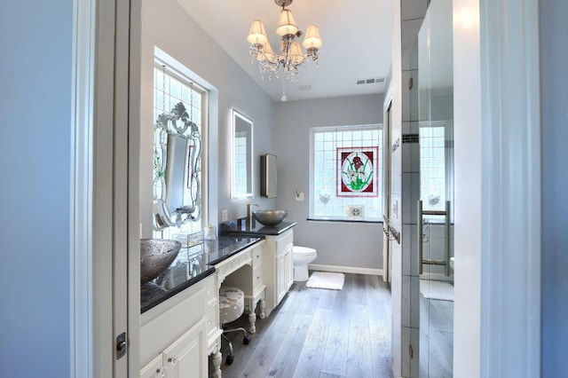full bathroom with a healthy amount of sunlight, visible vents, baseboards, toilet, and an inviting chandelier