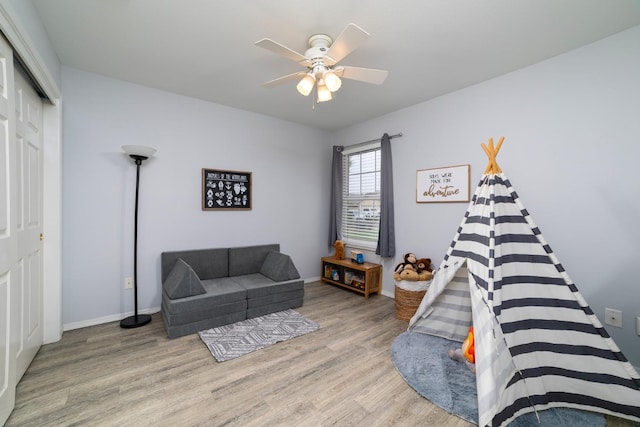 living room with wood finished floors, a ceiling fan, and baseboards