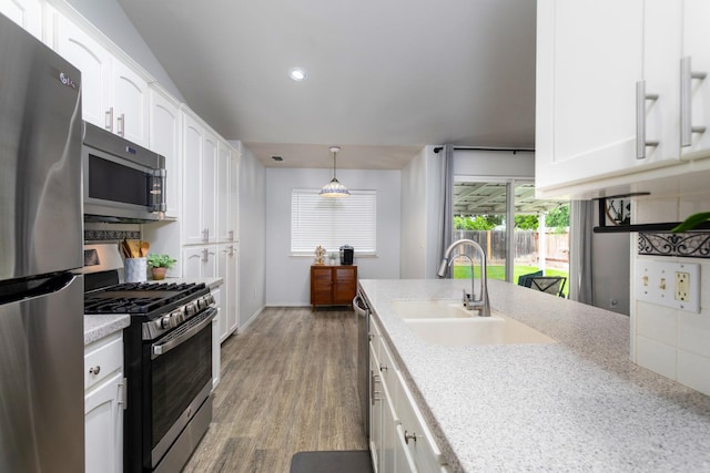 kitchen with white cabinets, stainless steel appliances, wood finished floors, and a sink