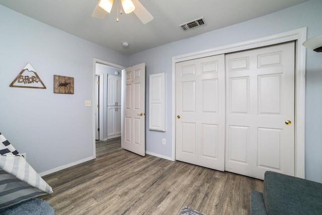 unfurnished bedroom featuring baseboards, visible vents, a ceiling fan, wood finished floors, and a closet