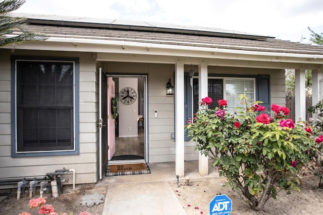 view of exterior entry with solar panels and a porch