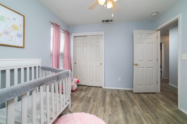 bedroom featuring baseboards, wood finished floors, visible vents, and a closet