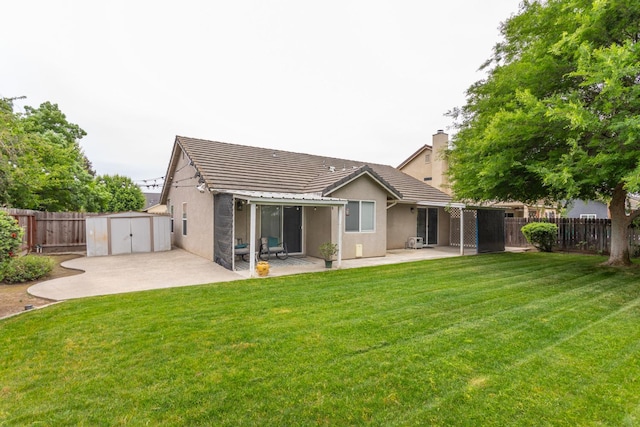 rear view of house featuring a storage unit, a patio area, a fenced backyard, and stucco siding