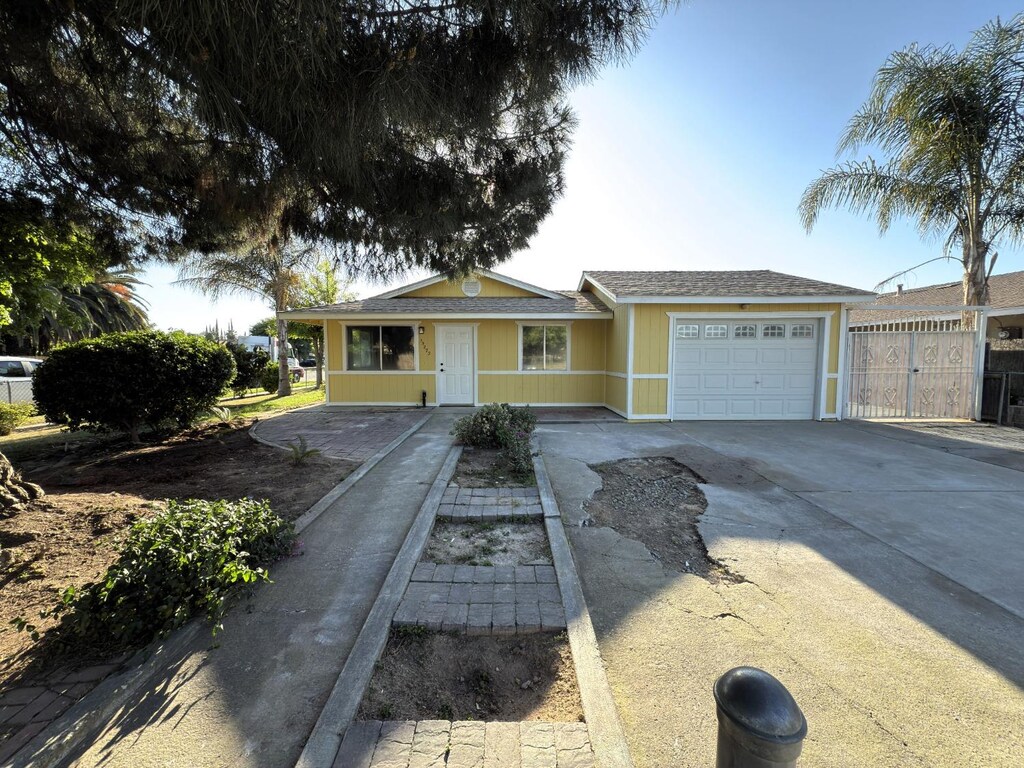 single story home with driveway, fence, and a garage