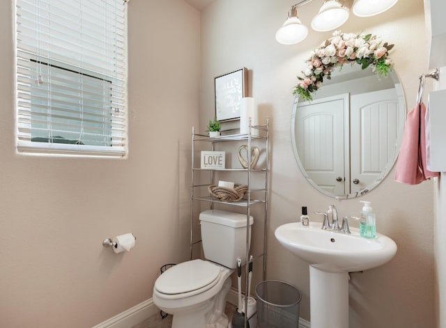 half bath featuring baseboards, a sink, and toilet