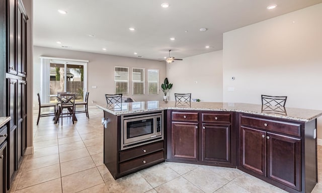 kitchen featuring stainless steel microwave, light tile patterned flooring, recessed lighting, a ceiling fan, and a kitchen island