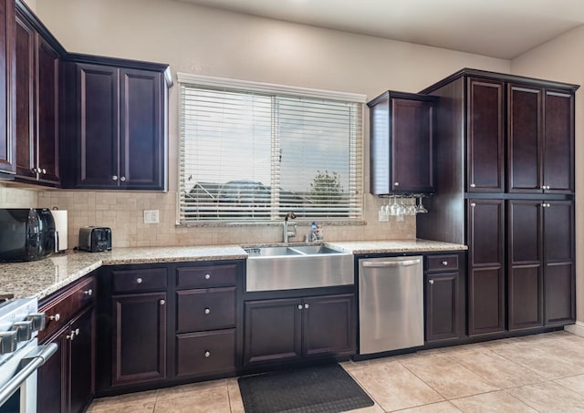 kitchen with a sink, backsplash, appliances with stainless steel finishes, light stone counters, and light tile patterned floors