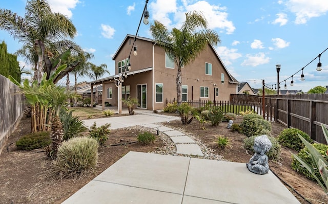 rear view of property with a patio area, fence private yard, and stucco siding