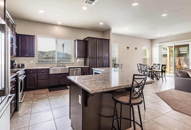kitchen featuring a breakfast bar, backsplash, appliances with stainless steel finishes, and a sink