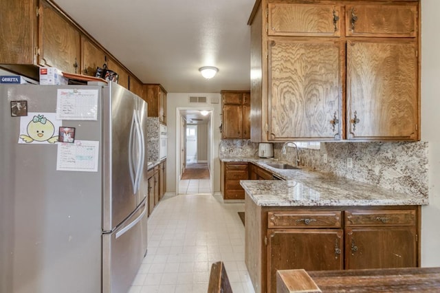 7341 N Bond St, Fresno, CA 93720 - kitchen with freestanding refrigerator, brown cabinetry, decorative backsplash, and a sink