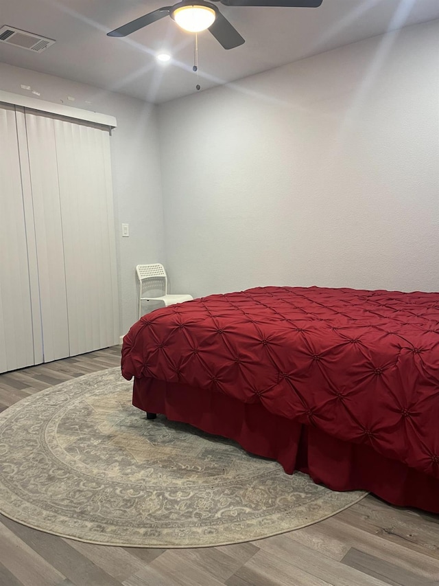 bedroom with a ceiling fan, wood finished floors, and visible vents