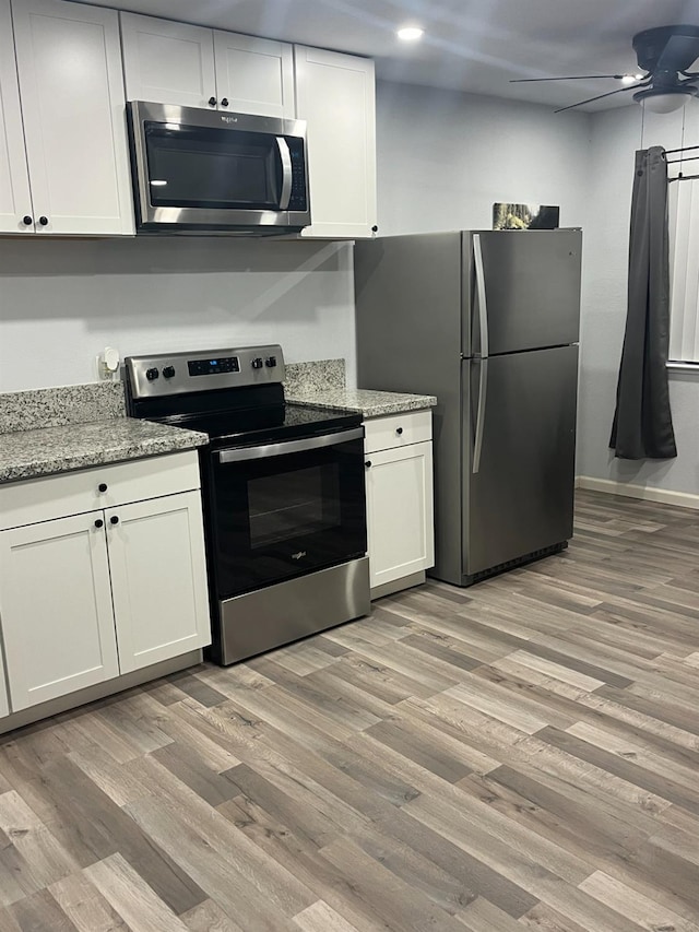 kitchen with light wood-style floors, a ceiling fan, appliances with stainless steel finishes, and white cabinets