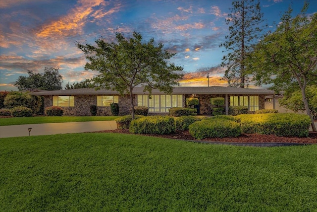 view of front of home featuring stone siding and a front lawn