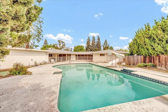 view of swimming pool featuring a water slide, fence, a patio area, and a fenced in pool