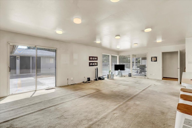 unfurnished living room with a wealth of natural light and carpet flooring