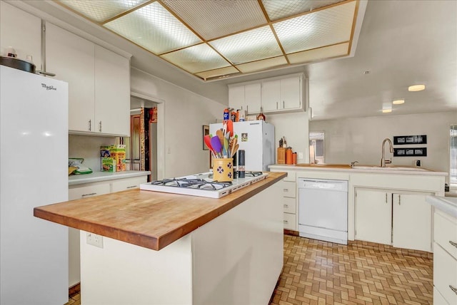 kitchen with wood counters, white cabinets, a sink, and white appliances