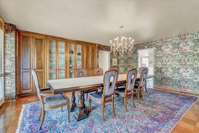 dining room featuring wallpapered walls, baseboards, and an inviting chandelier