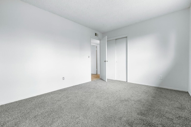 unfurnished bedroom with light carpet, visible vents, a textured ceiling, and a closet