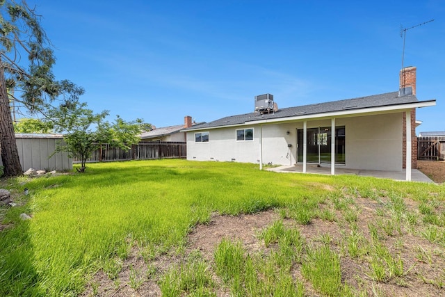 rear view of property featuring a patio area, a fenced backyard, a chimney, and a yard