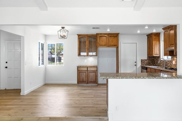 kitchen featuring tasteful backsplash, brown cabinets, light wood finished floors, light stone countertops, and recessed lighting