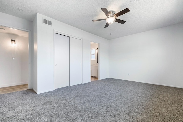 unfurnished bedroom with visible vents, a closet, baseboards, a textured ceiling, and carpet flooring