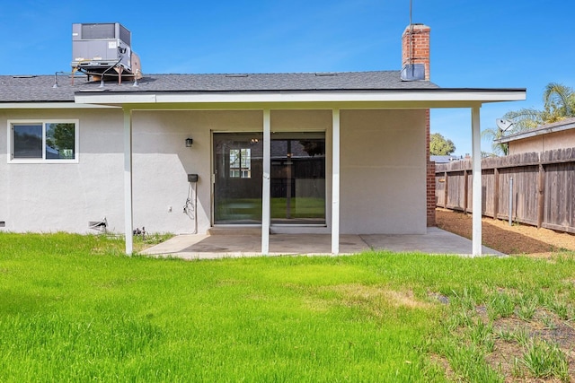back of property featuring central AC, a patio area, a lawn, fence, and stucco siding
