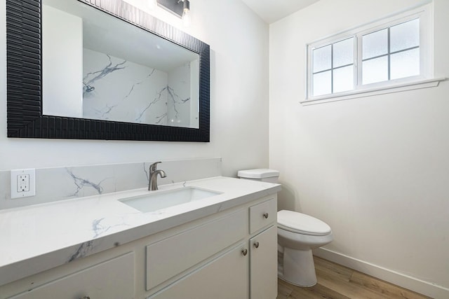 bathroom with baseboards, wood finished floors, toilet, and vanity