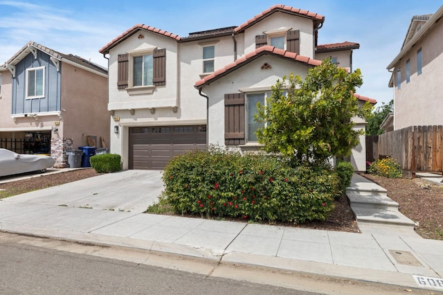 6082 E Homan Ave, Fresno, CA 93727 - mediterranean / spanish house featuring a tiled roof, an attached garage, stucco siding, and concrete driveway