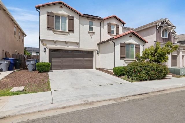 6082 E Homan Ave, Fresno, CA 93727 - mediterranean / spanish-style home with an attached garage, a tile roof, stucco siding, and concrete driveway