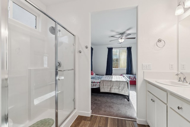 ensuite bathroom featuring wood finished floors, vanity, a stall shower, ceiling fan, and ensuite bathroom