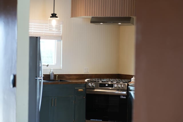 1016 N White St, Hanford, CA 93230 - kitchen with dark countertops, a sink, pendant lighting, appliances with stainless steel finishes, and under cabinet range hood