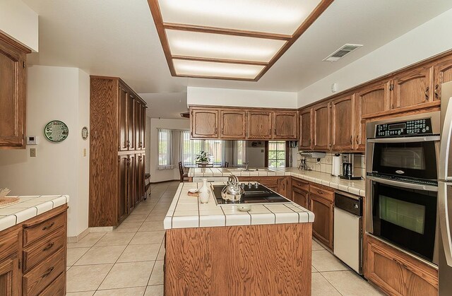 7355 N Pacific Ave, Fresno, CA 93711 - kitchen featuring black electric cooktop, light tile patterned flooring, visible vents, tile countertops, and double oven