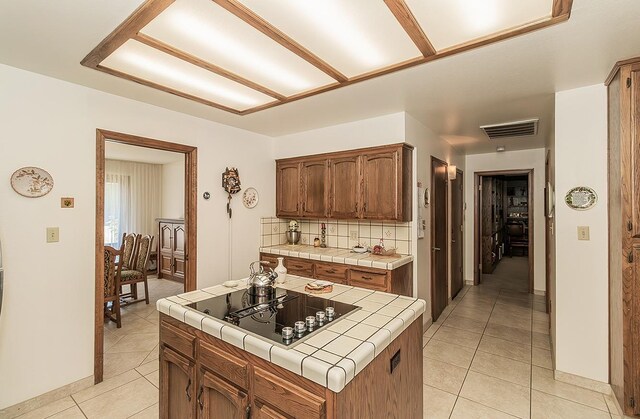 7355 N Pacific Ave, Fresno, CA 93711 - kitchen with tile countertops, light tile patterned floors, black electric cooktop, backsplash, and visible vents