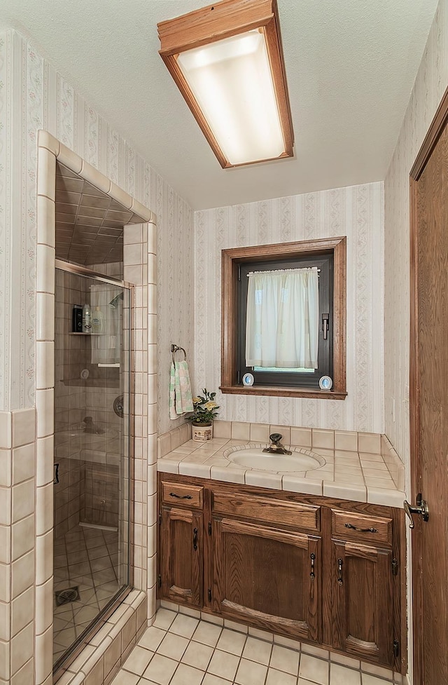 7355 N Pacific Ave, Fresno, CA 93711 - full bathroom with tile patterned floors, a textured ceiling, wallpapered walls, a shower stall, and vanity