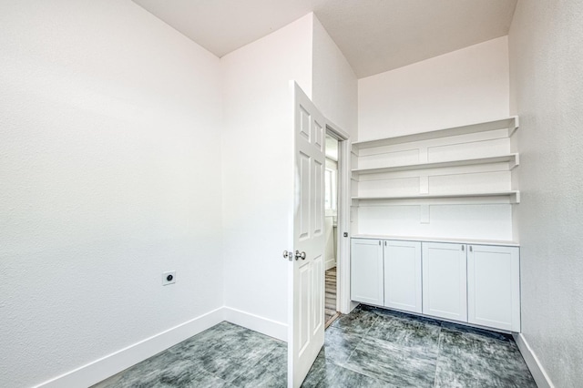 clothes washing area featuring electric dryer hookup, baseboards, a textured wall, and laundry area
