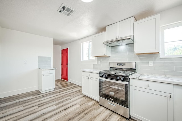 kitchen featuring light wood-style flooring, visible vents, baseboards, under cabinet range hood, and stainless steel gas range oven