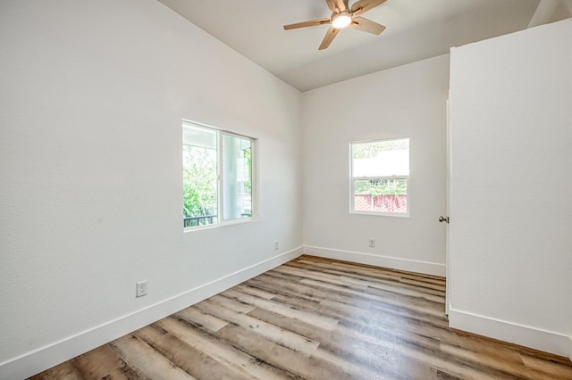 spare room with vaulted ceiling, wood finished floors, a ceiling fan, and baseboards