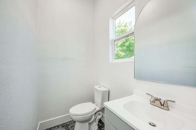 bathroom featuring baseboards, toilet, and vanity
