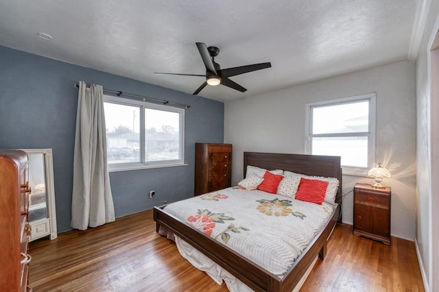 bedroom featuring a ceiling fan, wood finished floors, and multiple windows