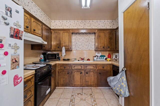 4311 N Emerson Ave, Fresno, CA 93705 - kitchen with black range with electric cooktop, light tile patterned floors, stainless steel microwave, under cabinet range hood, and freestanding refrigerator