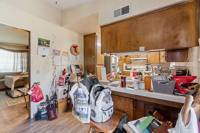 4311 N Emerson Ave, Fresno, CA 93705 - interior space featuring white electric range oven, tile counters, brown cabinets, light wood finished floors, and visible vents