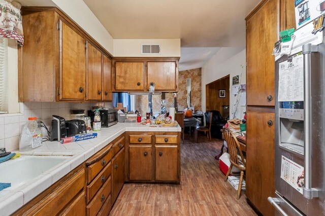 4311 N Emerson Ave, Fresno, CA 93705 - kitchen with brown cabinets, tile counters, stainless steel fridge with ice dispenser, visible vents, and light wood-type flooring