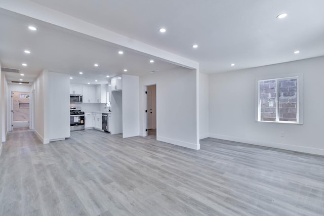 227 E Pine Ave, Fresno, CA 93728 - unfurnished living room featuring baseboards, recessed lighting, light wood-style flooring, and a sink