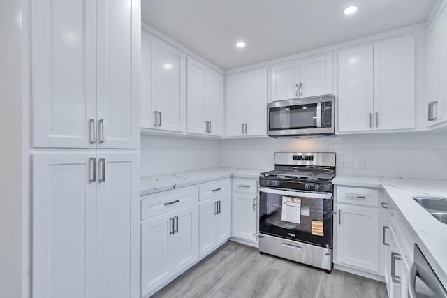 227 E Pine Ave, Fresno, CA 93728 - kitchen featuring stainless steel appliances, white cabinets, light wood-style flooring, light stone counters, and recessed lighting