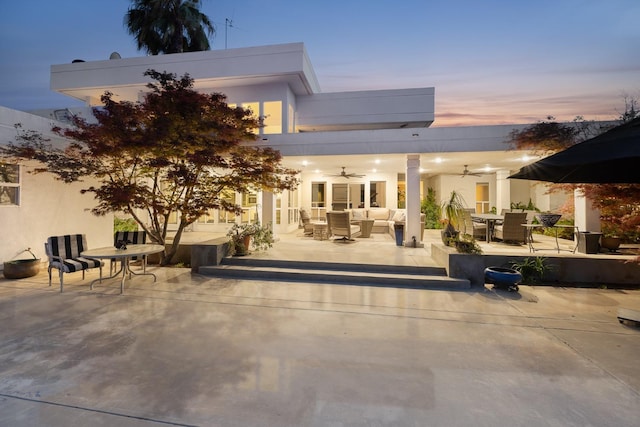 back of property at dusk with a ceiling fan, an outdoor hangout area, stucco siding, a patio area, and outdoor dining area