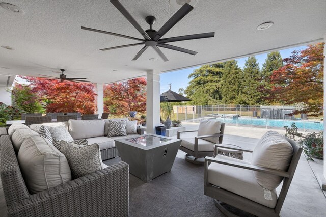 view of patio featuring fence, a fenced in pool, a ceiling fan, and an outdoor living space with a fire pit