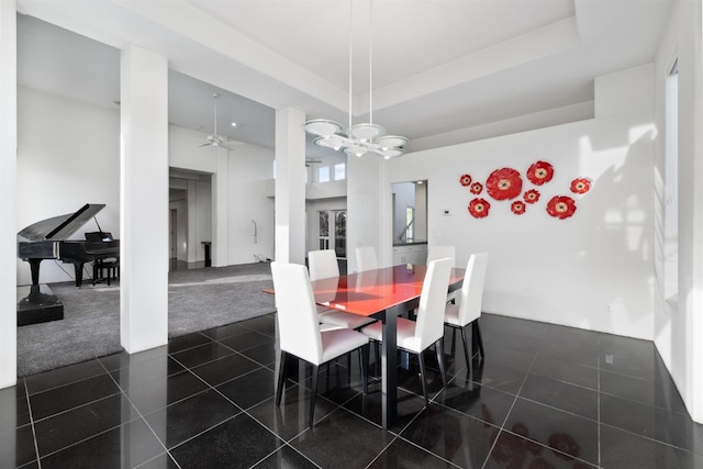 dining room featuring a tray ceiling, dark tile patterned floors, and ceiling fan with notable chandelier