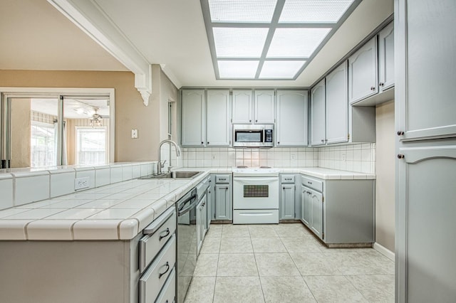 5711 W Fallon Ave, Fresno, CA 93722 - kitchen with tasteful backsplash, electric stove, tile countertops, stainless steel microwave, and dishwashing machine